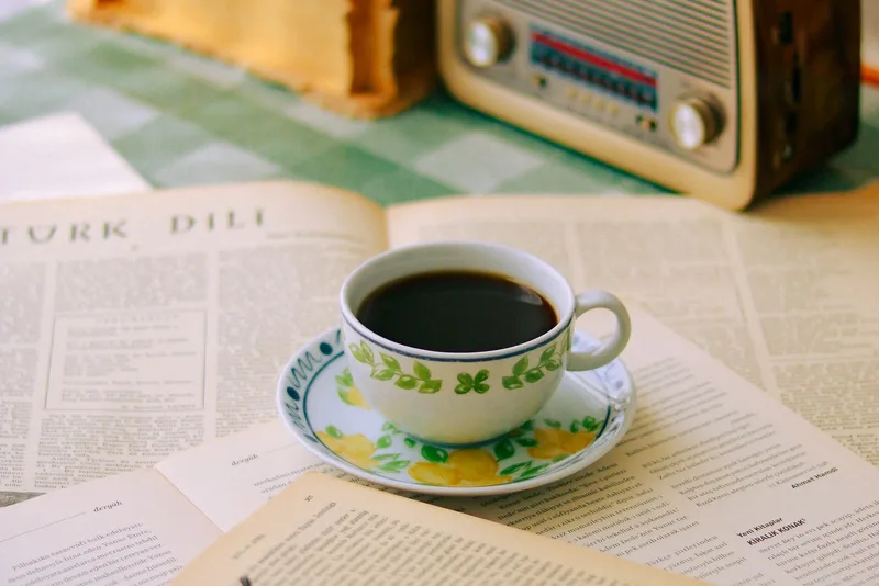 Mesa de estudio con una radio antigua, un libro y anteojos